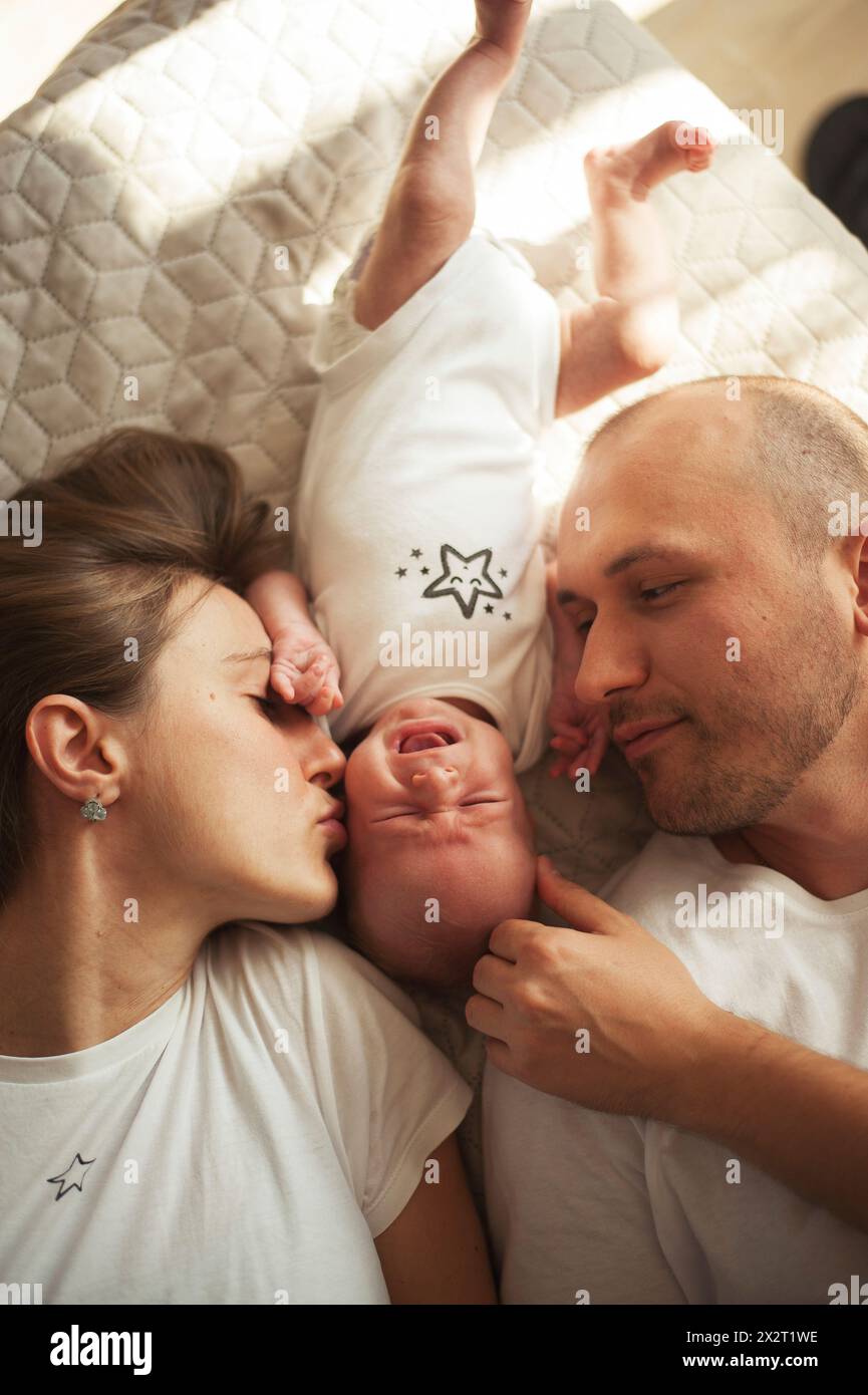 Parent lying on bed with baby boy at home Stock Photo