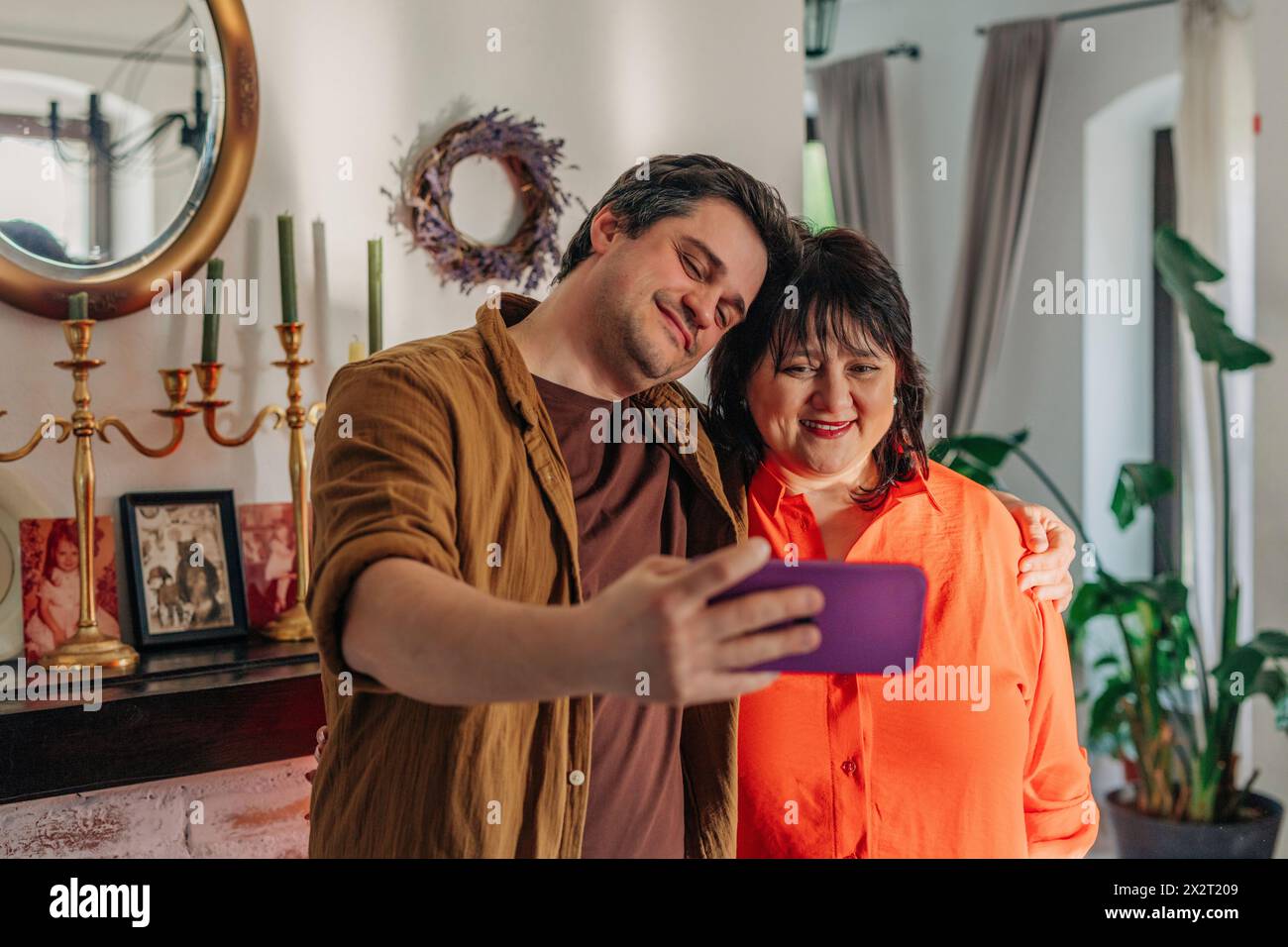 Smiling man taking selfie with mother at home Stock Photo