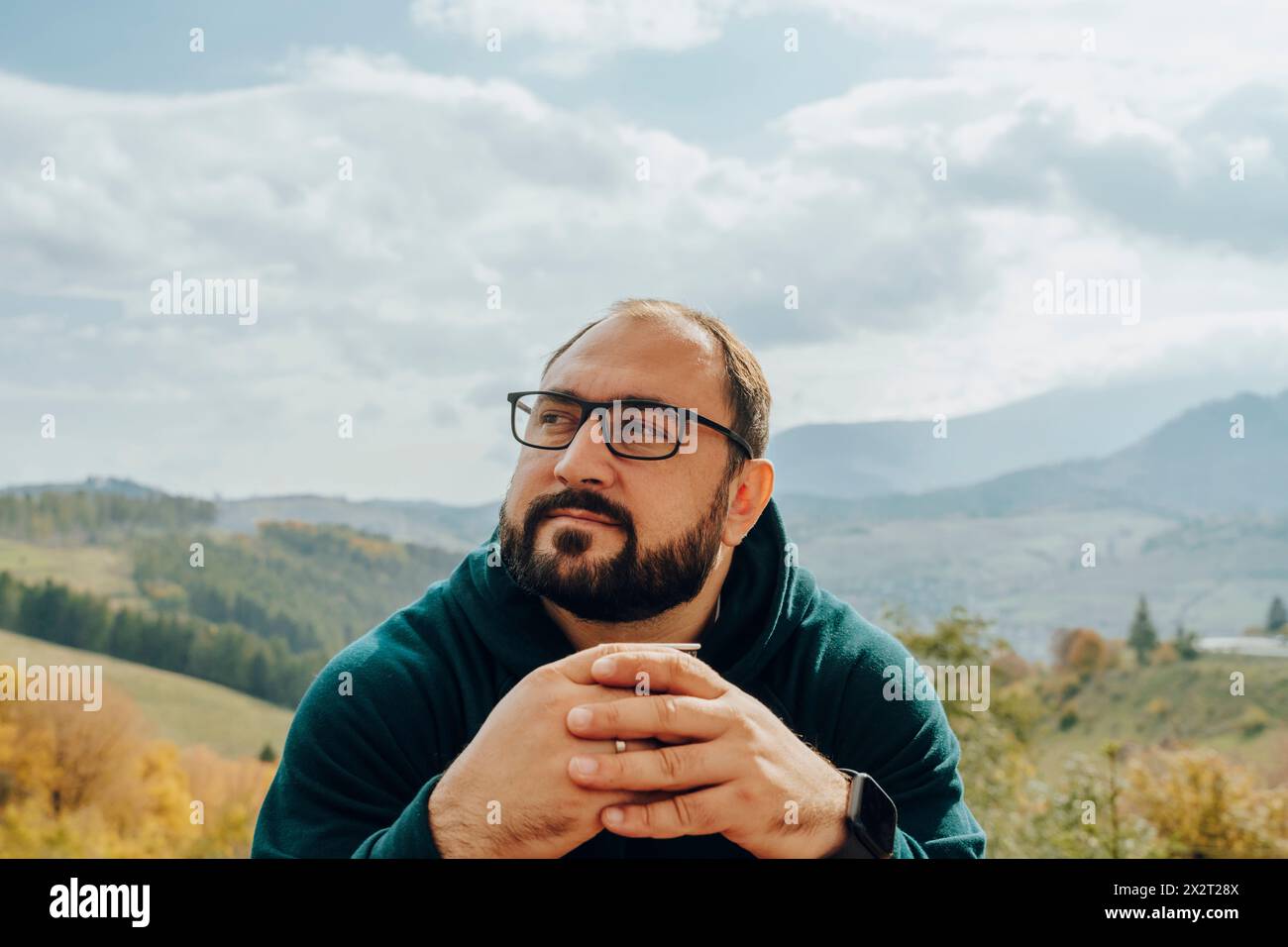 Bearded man with hands clasped wearing eyeglasses Stock Photo