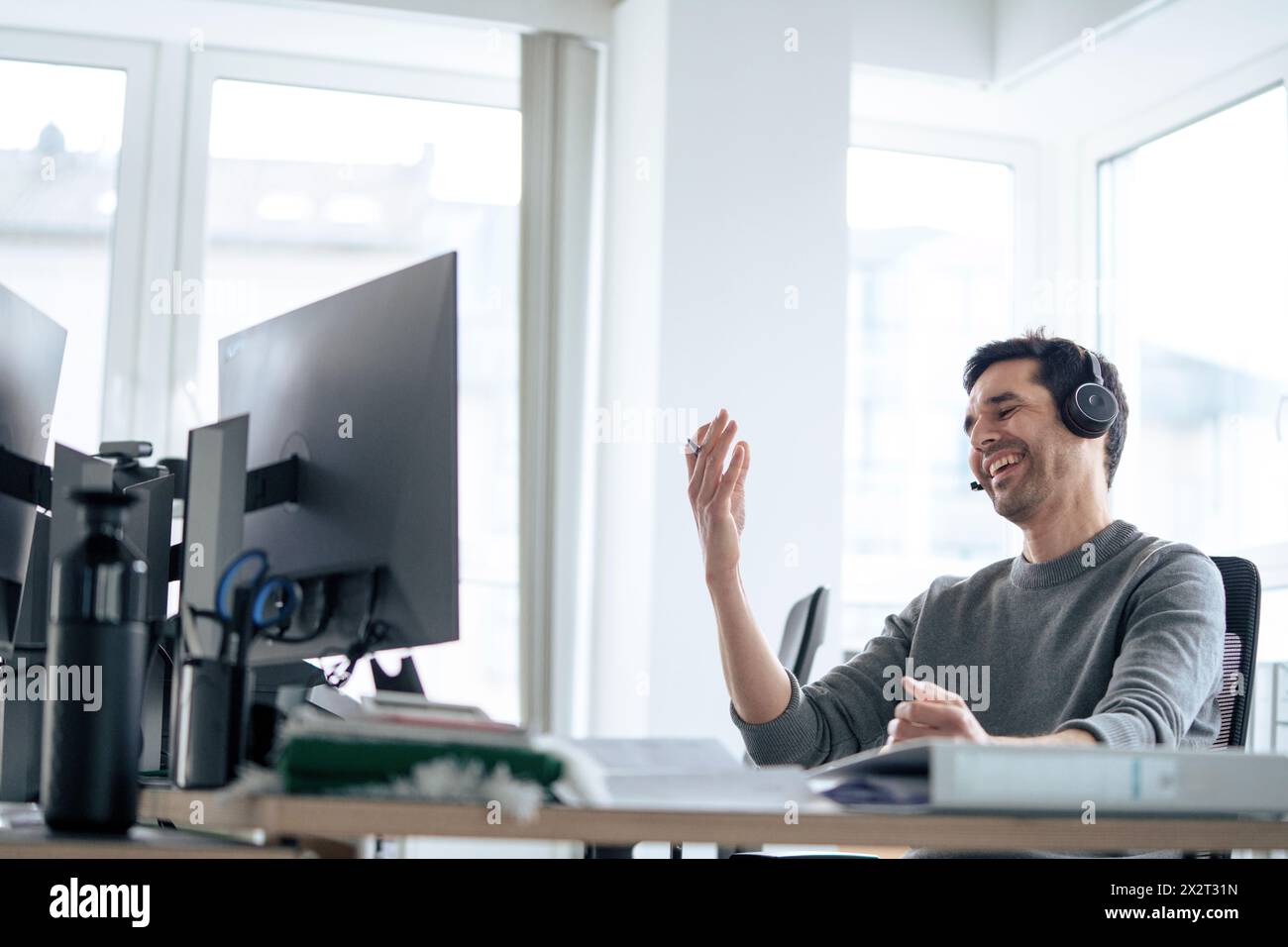 Happy businessman wearing headset and talking in office Stock Photo