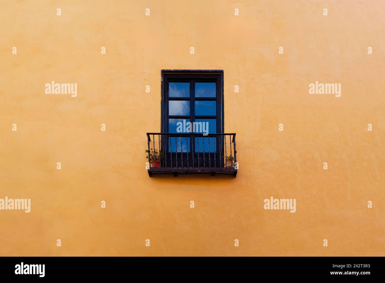 Empty window with balcony on yellow wall Stock Photo