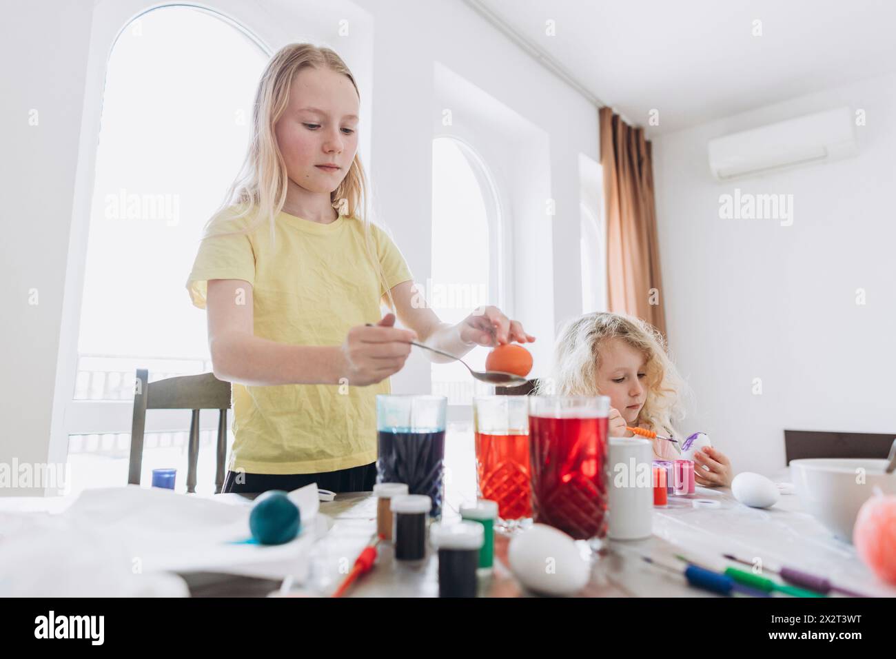 Sisters painting eggs for Easter at home Stock Photo
