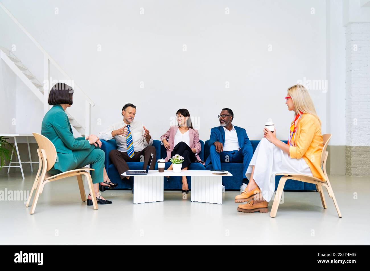Businessman discussing with multi-ethnic colleagues sitting at office Stock Photo