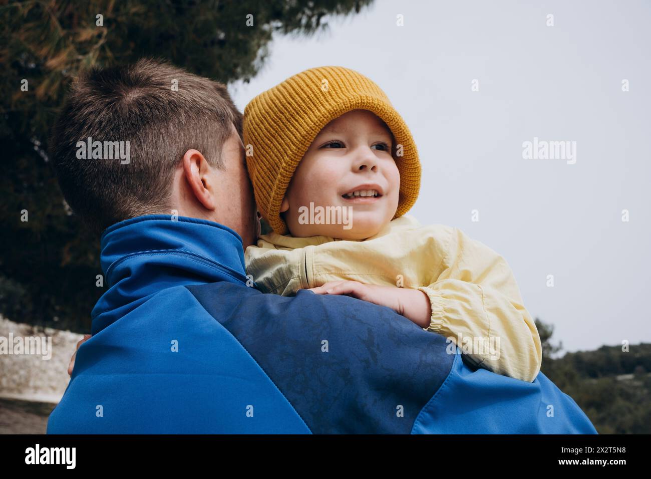 Father carrying son wearing knit hat Stock Photo