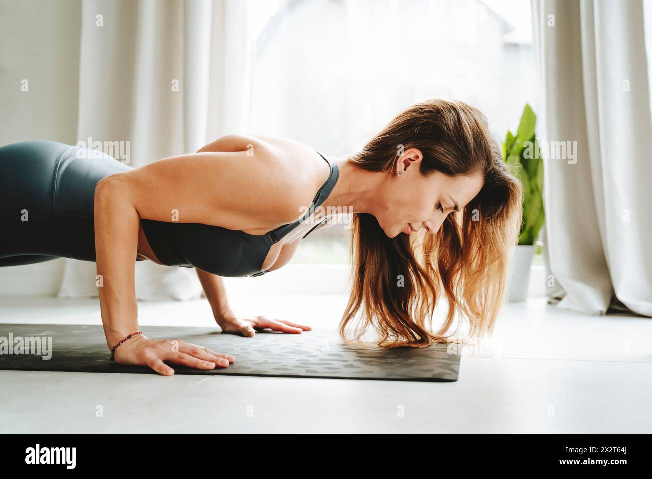Determined woman doing push-ups at home Stock Photo