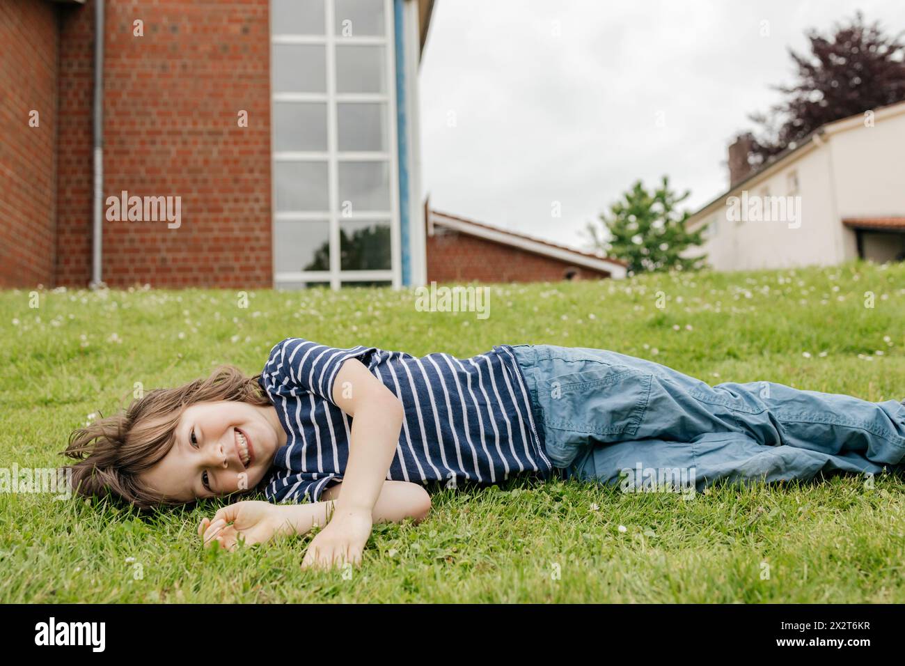 Happy boy lying down on grass in lawn Stock Photo