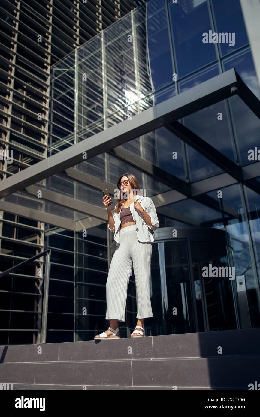 Businesswoman standing at entrance of modern office building Stock Photo