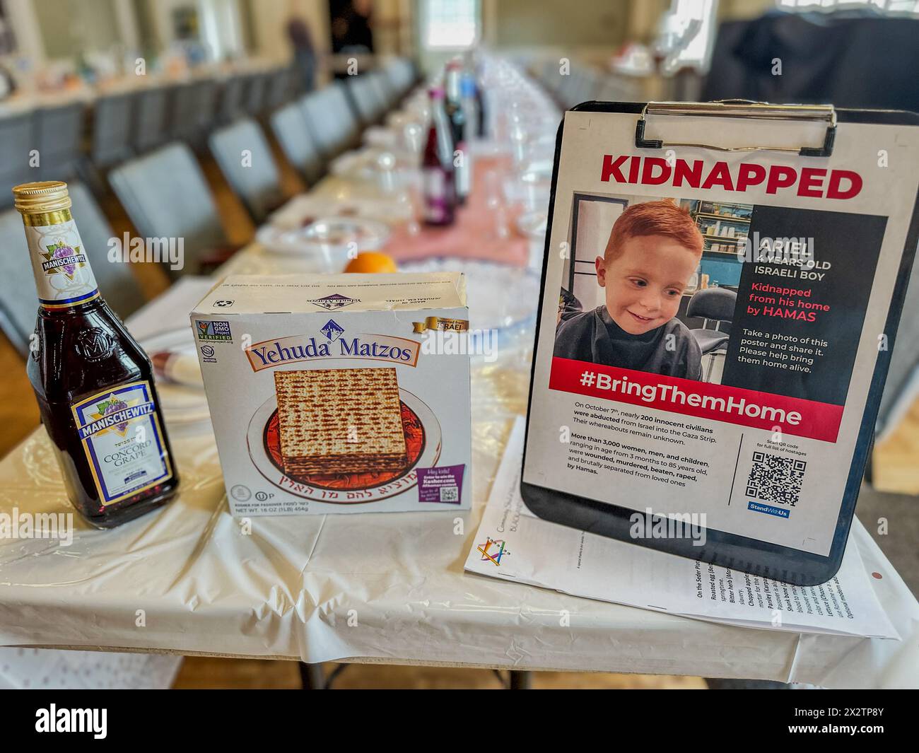 Montecito, California, U.S.A. 23rd Apr, 2024. A 'Kidnapped'' poster of Ariel, a four year old toddler kidnapped by Hamas, on a Passover table in Montecito, California, between a bottle of Kosher wine and a box of Matzos. This is hours before Jews will gather to celebrate Pesach ''” a ritual dinner where the story of how their ancestors in ancient times made the exodus from slavery in Egypt to freedom in Israel. The horrible attack by Hamas on Israel last fall and those hostages still being imprisoned in war-torn Palestine is a present day reminder of the bitterness of oppression, which is a Stock Photo