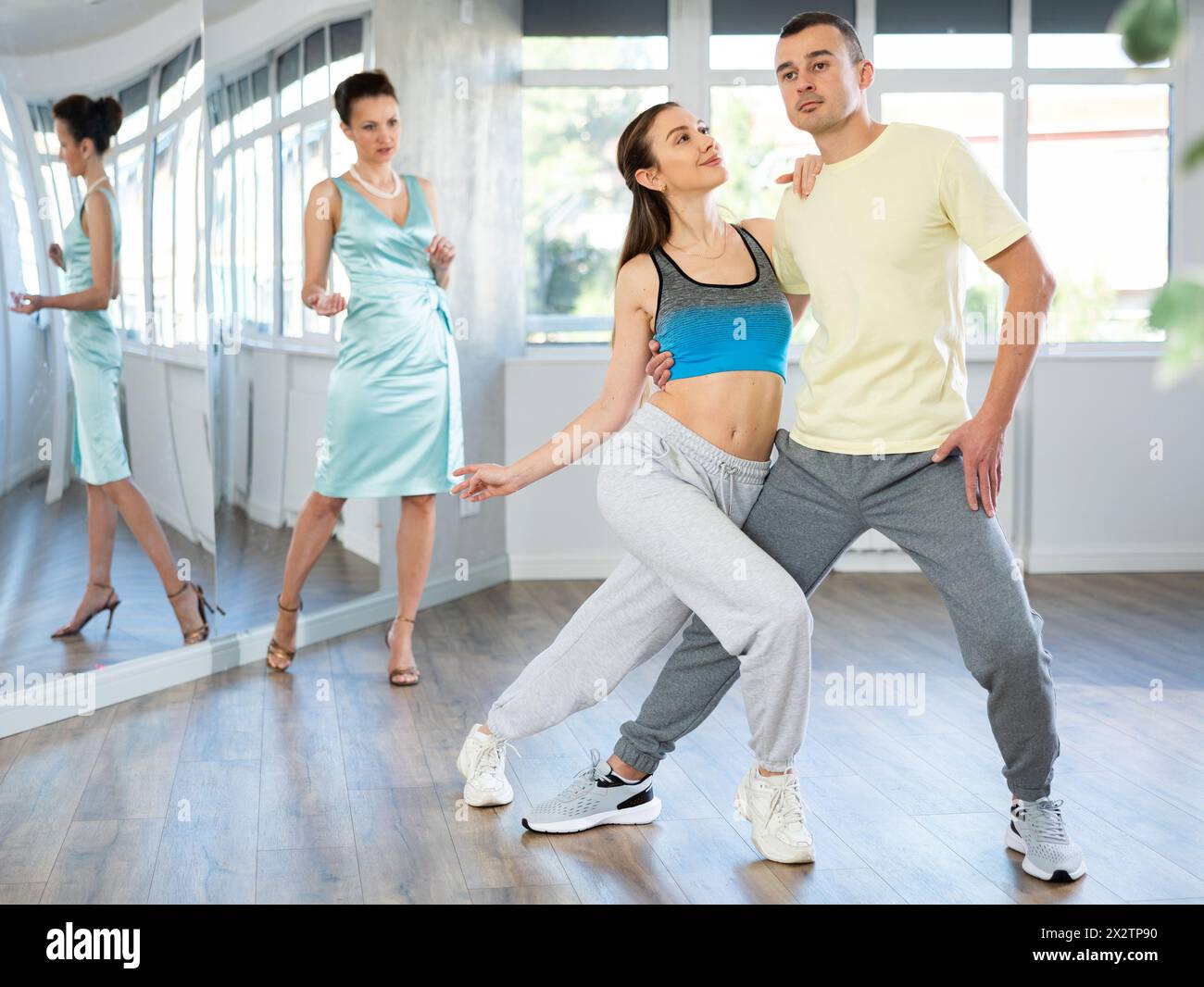 Couple practicing passionate tango guided by female dance instructor in studio Stock Photo