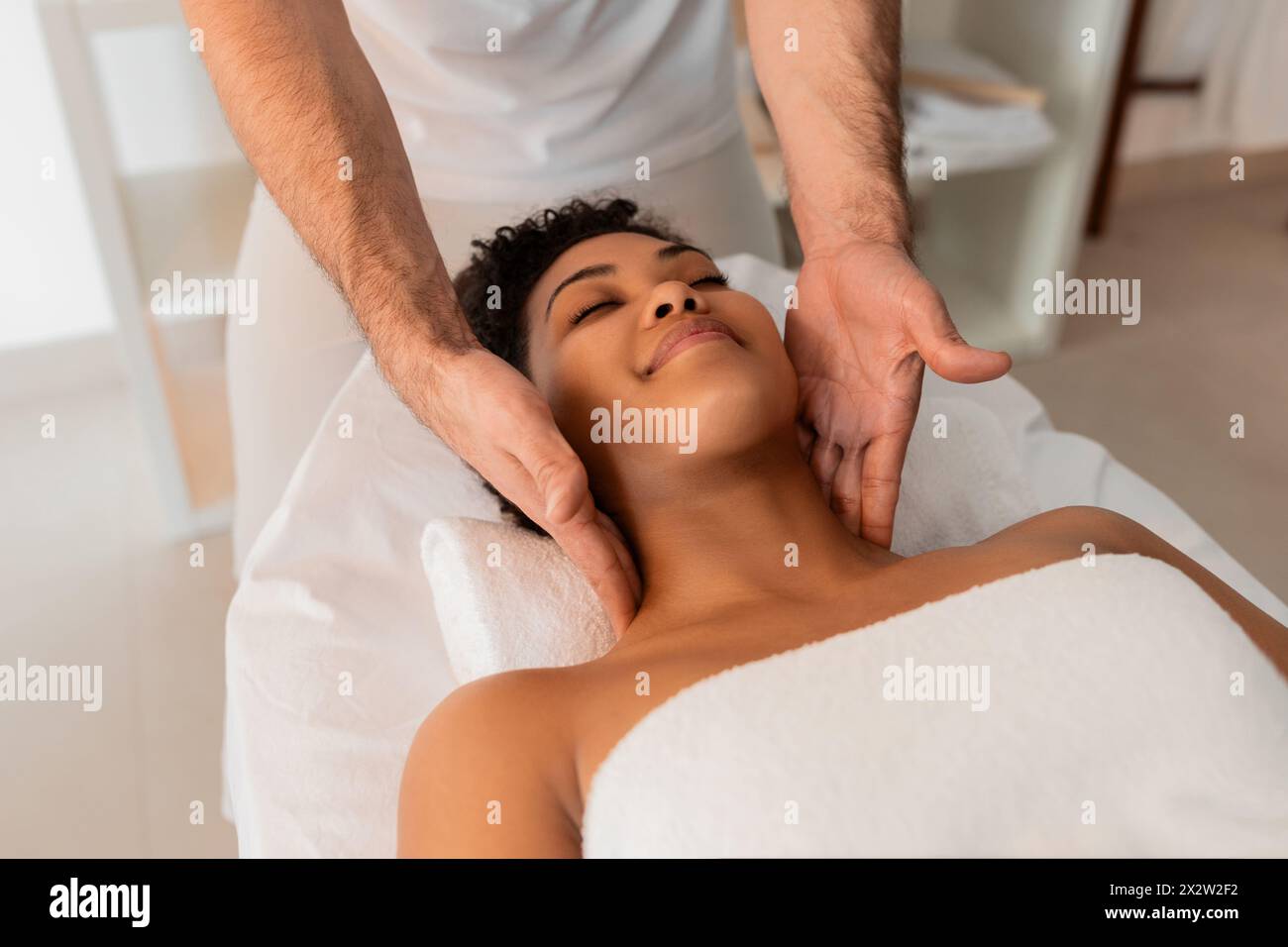Professional massaging the neck of a black lady Stock Photo