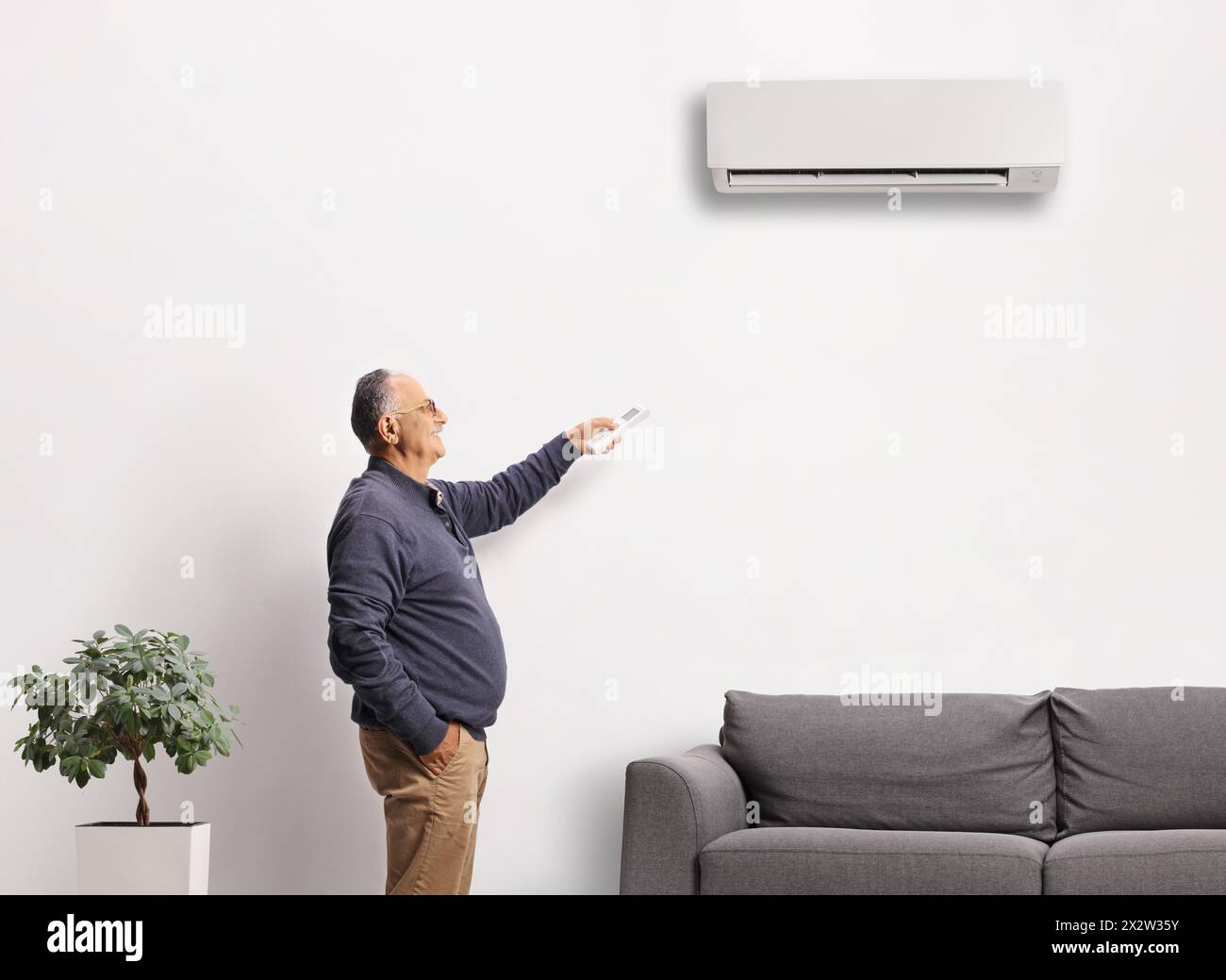 Mature man holding a remote controller from an air conditioning unit at home Stock Photo