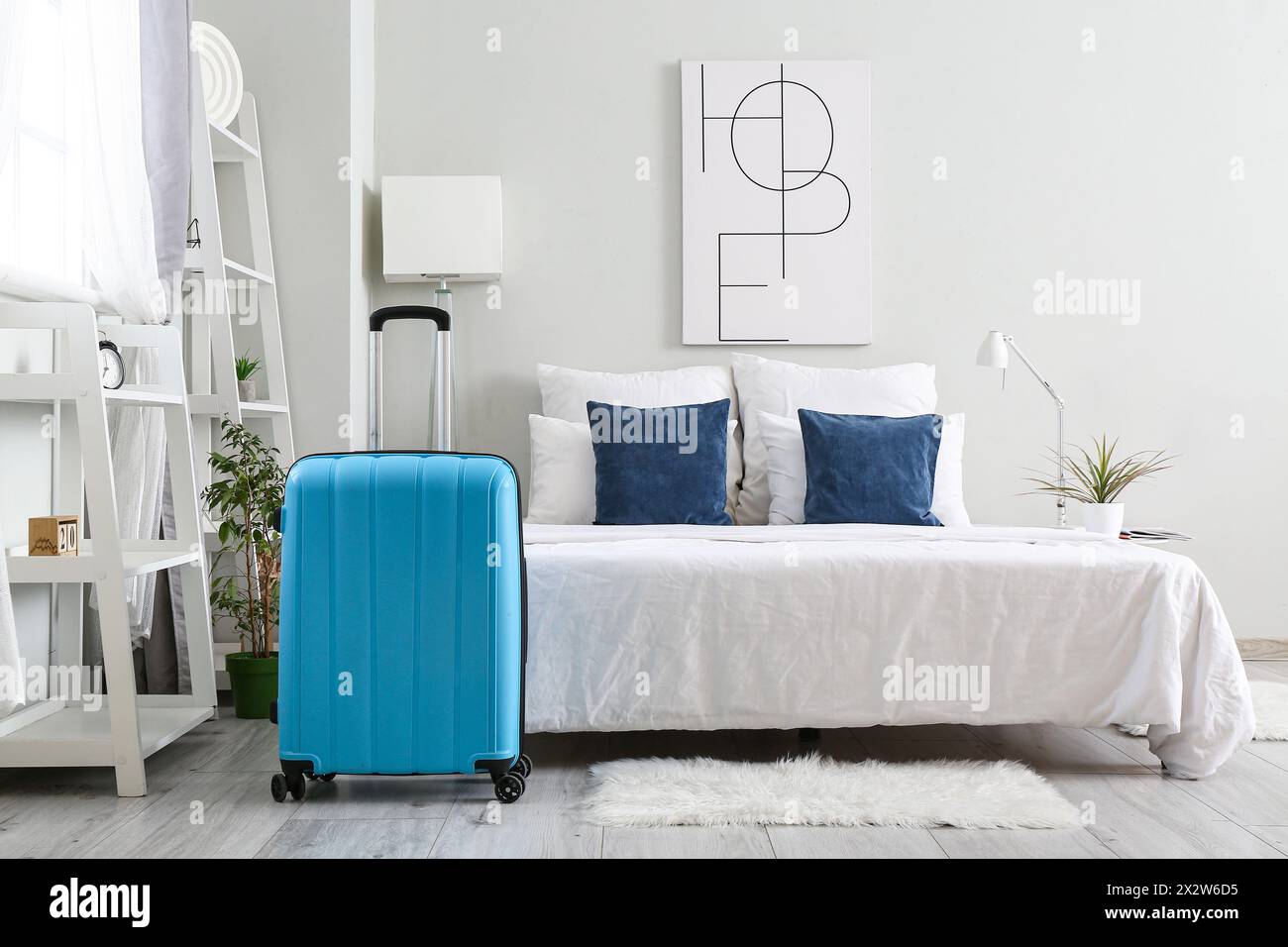 Interior of light hotel room with suitcase near bed Stock Photo