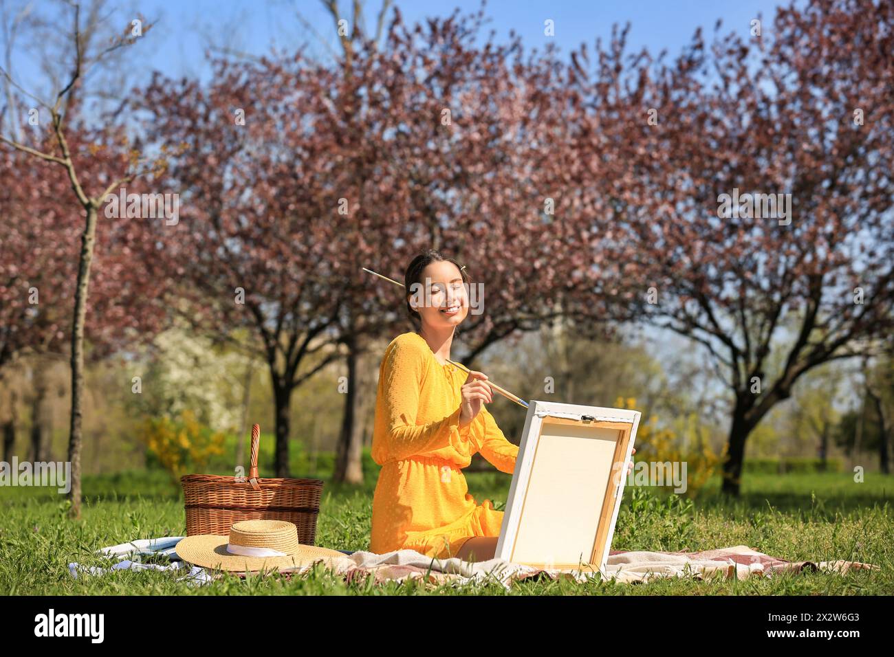 Beautiful young woman painting in park on spring day Stock Photo