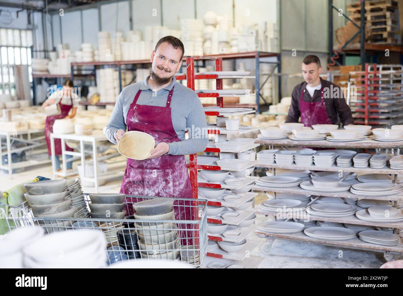 Enthusiastic ceramicist demonstrating handcrafted plates in ceramic studio Stock Photo