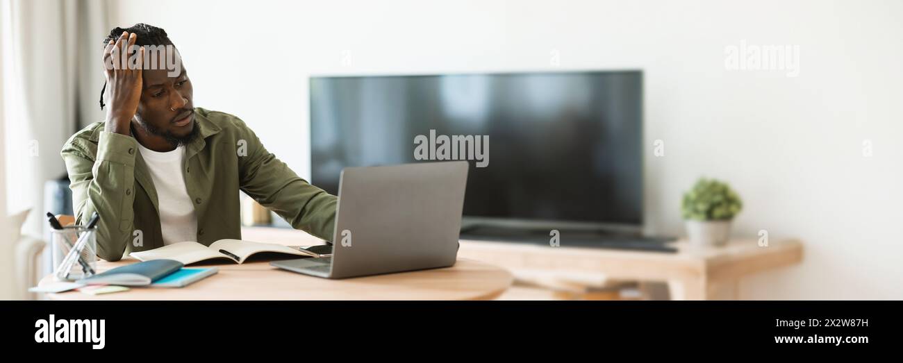 Thoughtful black man using laptop computer at home office Stock Photo