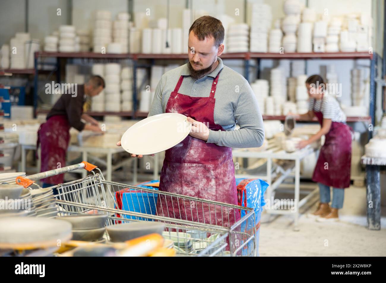 Ceramicist Examining Batch Of Slipcast Pottery In Ceramic Workshop