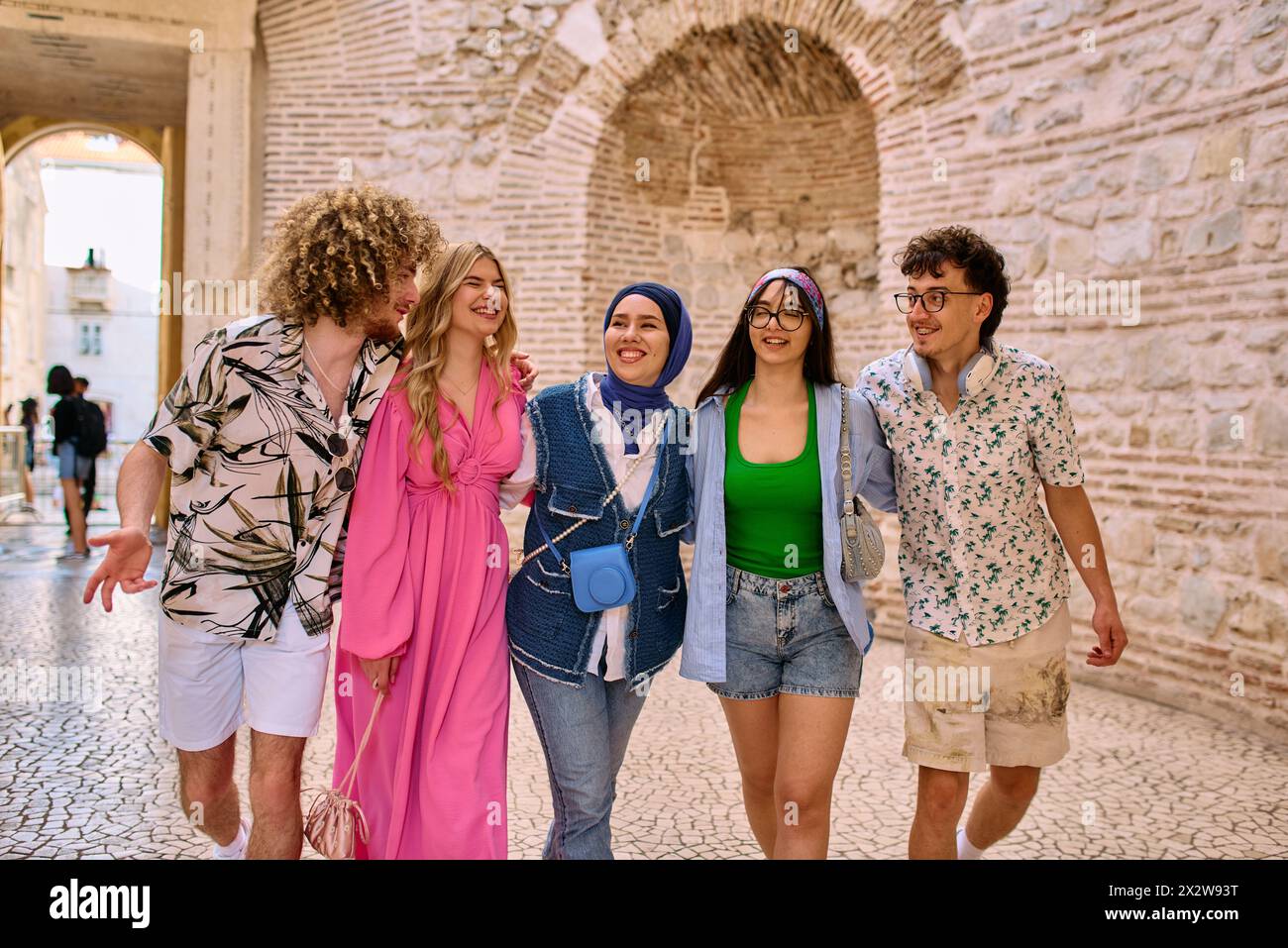 A diverse group of tourists, dressed in summer attire, strolls through