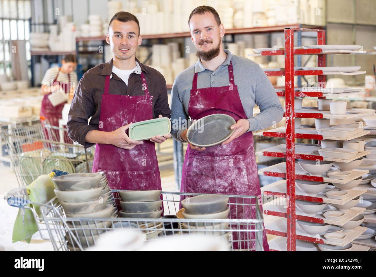Two potters holding handcrafted ceramic plates in pottery workshop Stock Photo