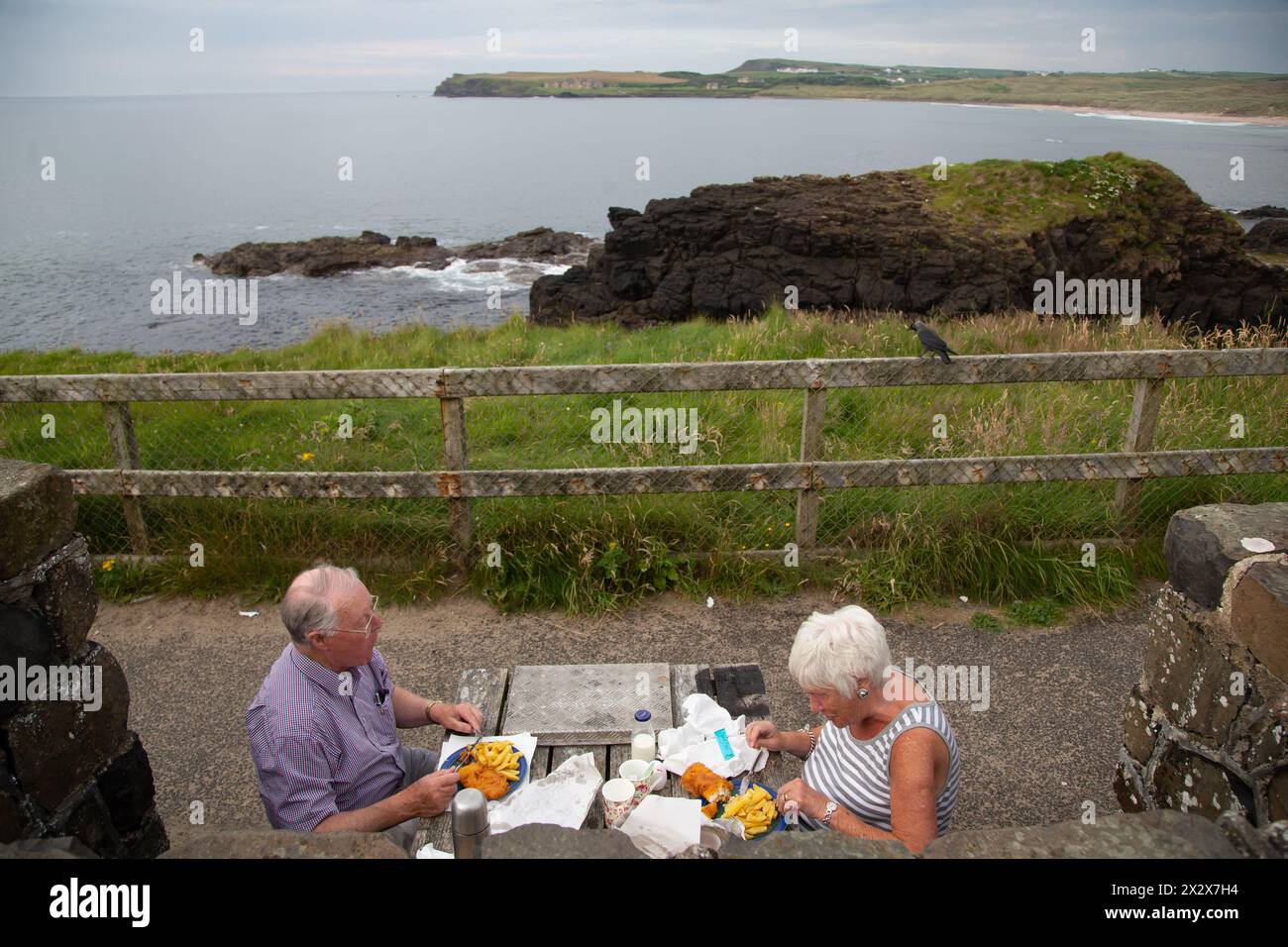16.07.2019, Portballintrae, Northern Ireland, United Kingdom - Happy retired couple eating fish and chips with a view of the Irish Sea. 00A190716D116C Stock Photo