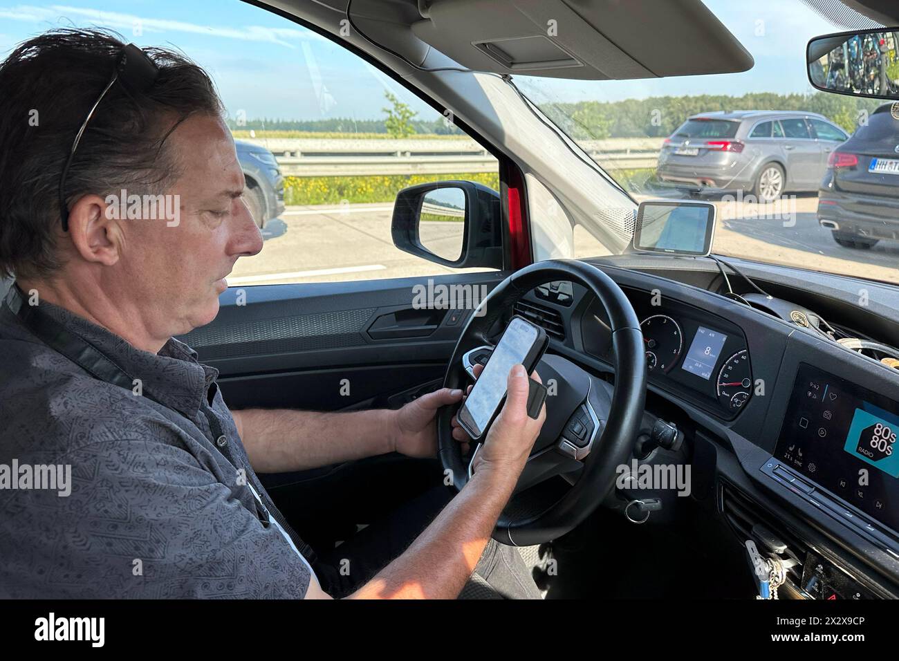 19.08.2023, Westenholz, Lower Saxony, Germany - Driver looking at his smartphone in a traffic jam on the A7. 00S230819D657CAROEX.JPG [MODEL RELEASE: Y Stock Photo