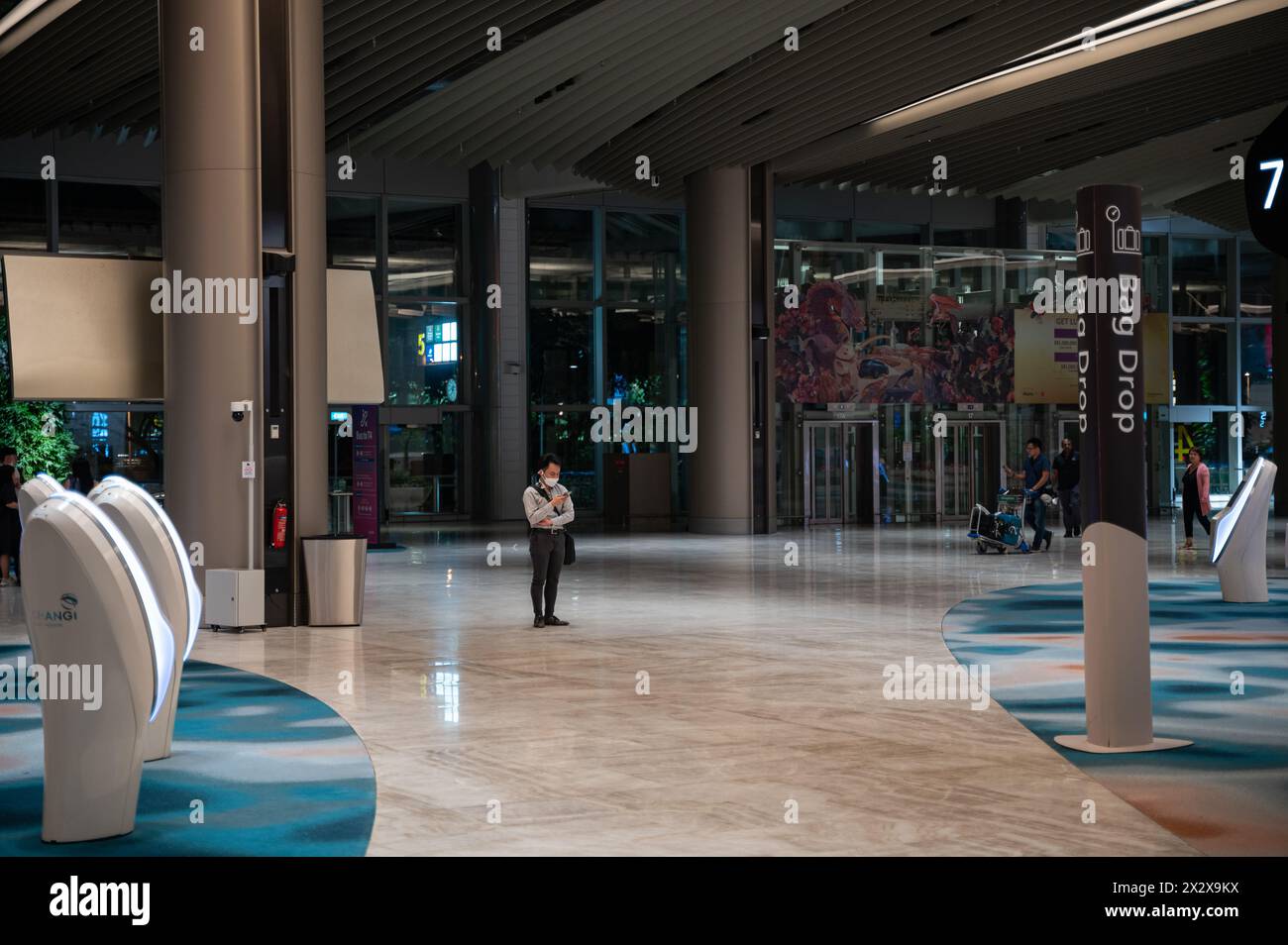 03.08.2023, Singapore, , Singapore - A passenger wearing a face mask stands in the modernized departure hall of Terminal 2 at Singapore Changi Airport Stock Photo