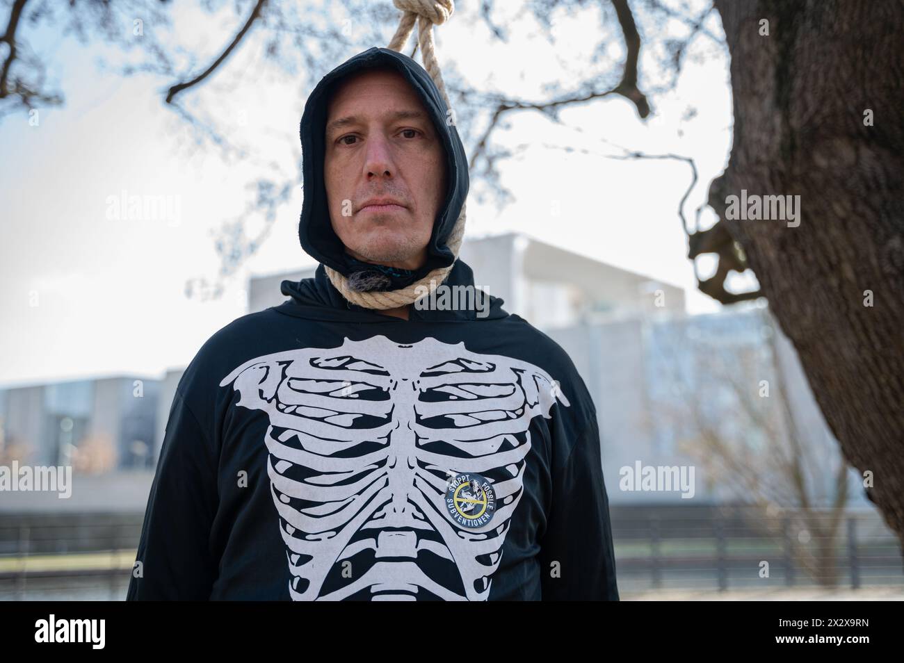 07.03.2024, Berlin, , Germany - Europe - German climate activist Wolfgang Wolli Metzeler-Kick wears a skeleton costume and stands with a noose around Stock Photo