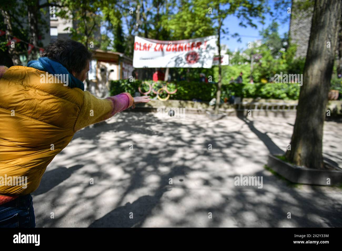 Players compete in petanque (boules game) beneath a placard reading “the Clap is in danger” at the Lepic Abbesses Petanque Club (Clap) in Paris, France on April 23, 2024. Petanque is a game similar to bowls that is as dear to the French as village cricket is to the English. During the Belle epoque, Montmartre was the artistic heart of Paris, home to Pablo Picasso, Claude Monet and Pierre-Auguste Renoir, who were attracted by its cheap rents and bohemian nightlife. Today the picturesque district that was one of the settings of the 2001 film Amelie is a magnet for tourists. Property prices have Stock Photo