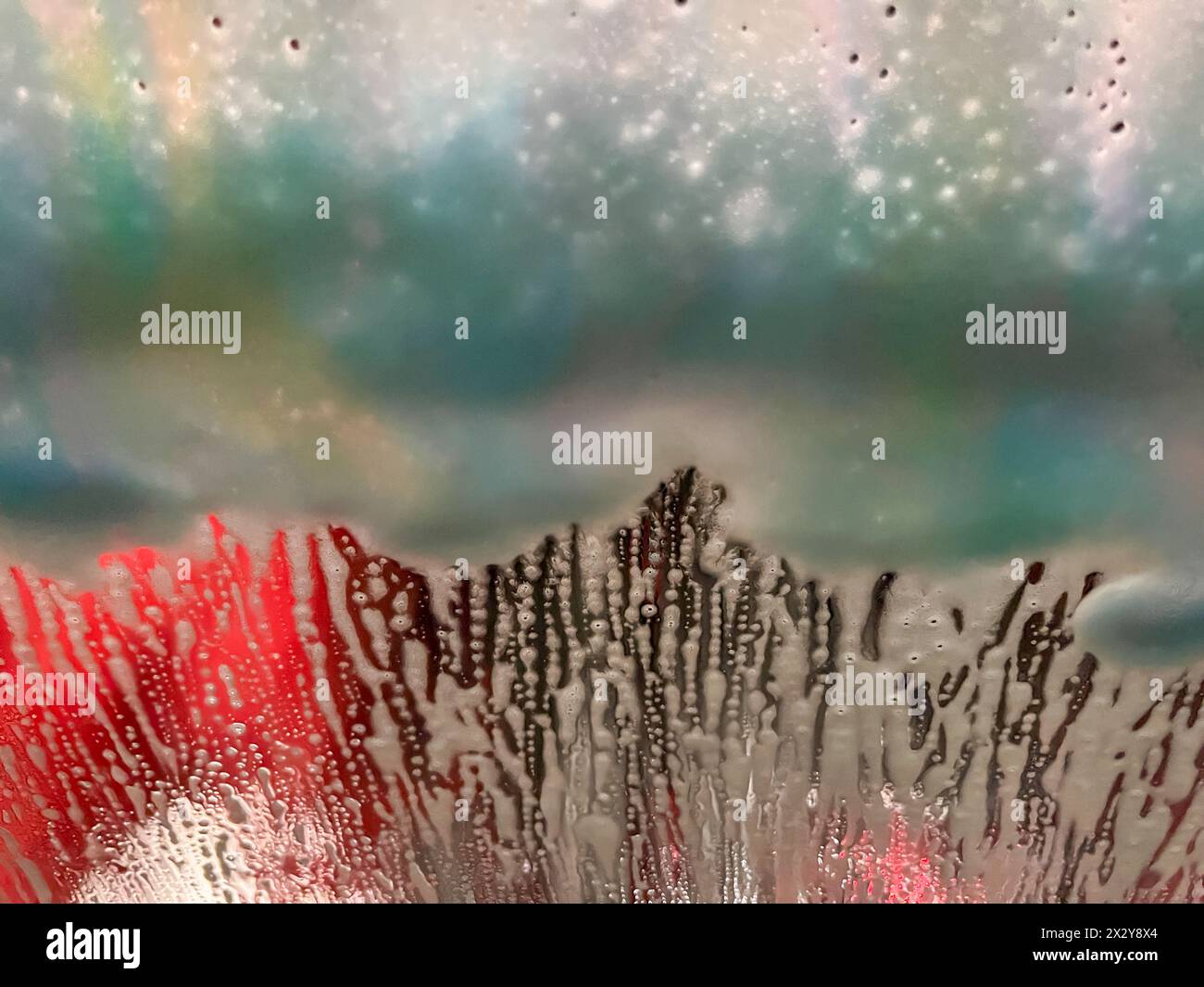 Abstract texture background of soap and water designs on a vehicle windshield in an automated car wash Stock Photo