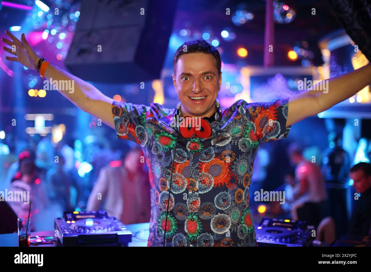 DJ in a club in colored shirt raised his hands up Stock Photo