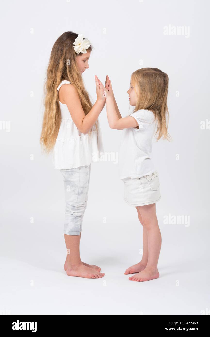Two girls dressed in white playing slapping each others hands Stock Photo