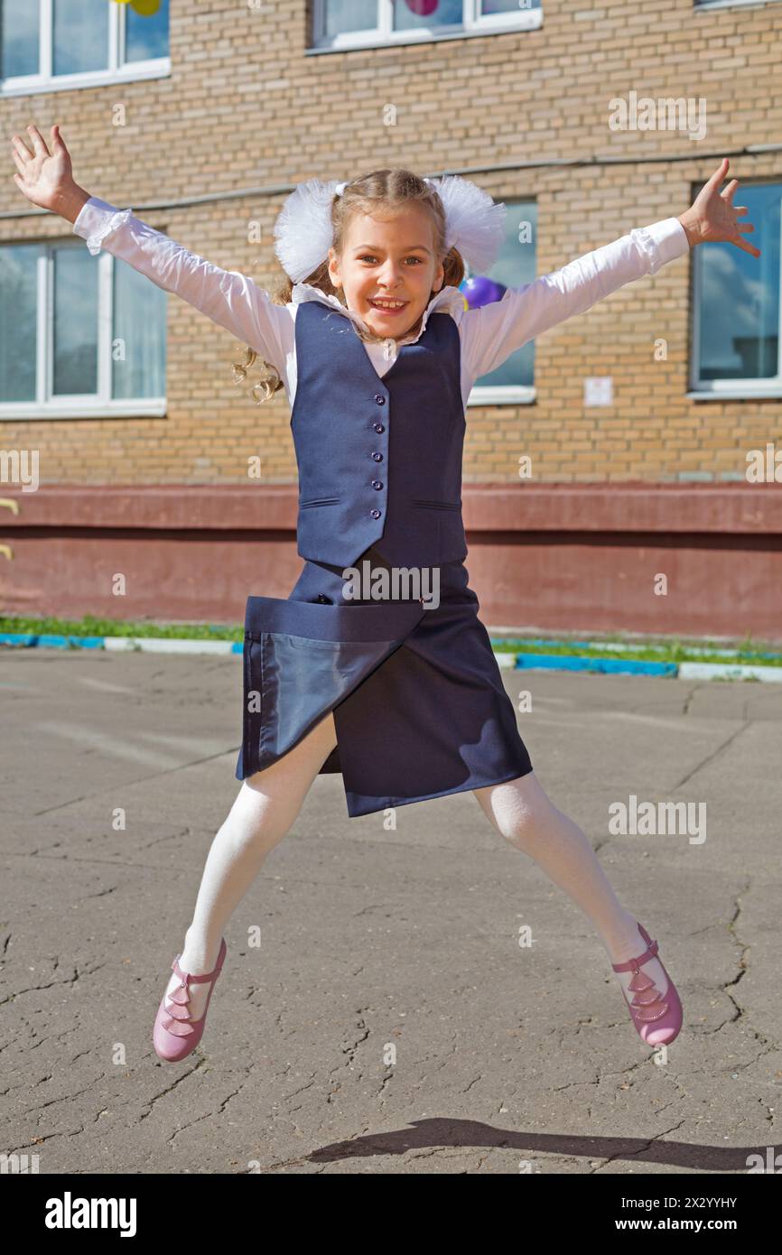 Happy little schoolgirl jumping raising his hands up Stock Photo - Alamy