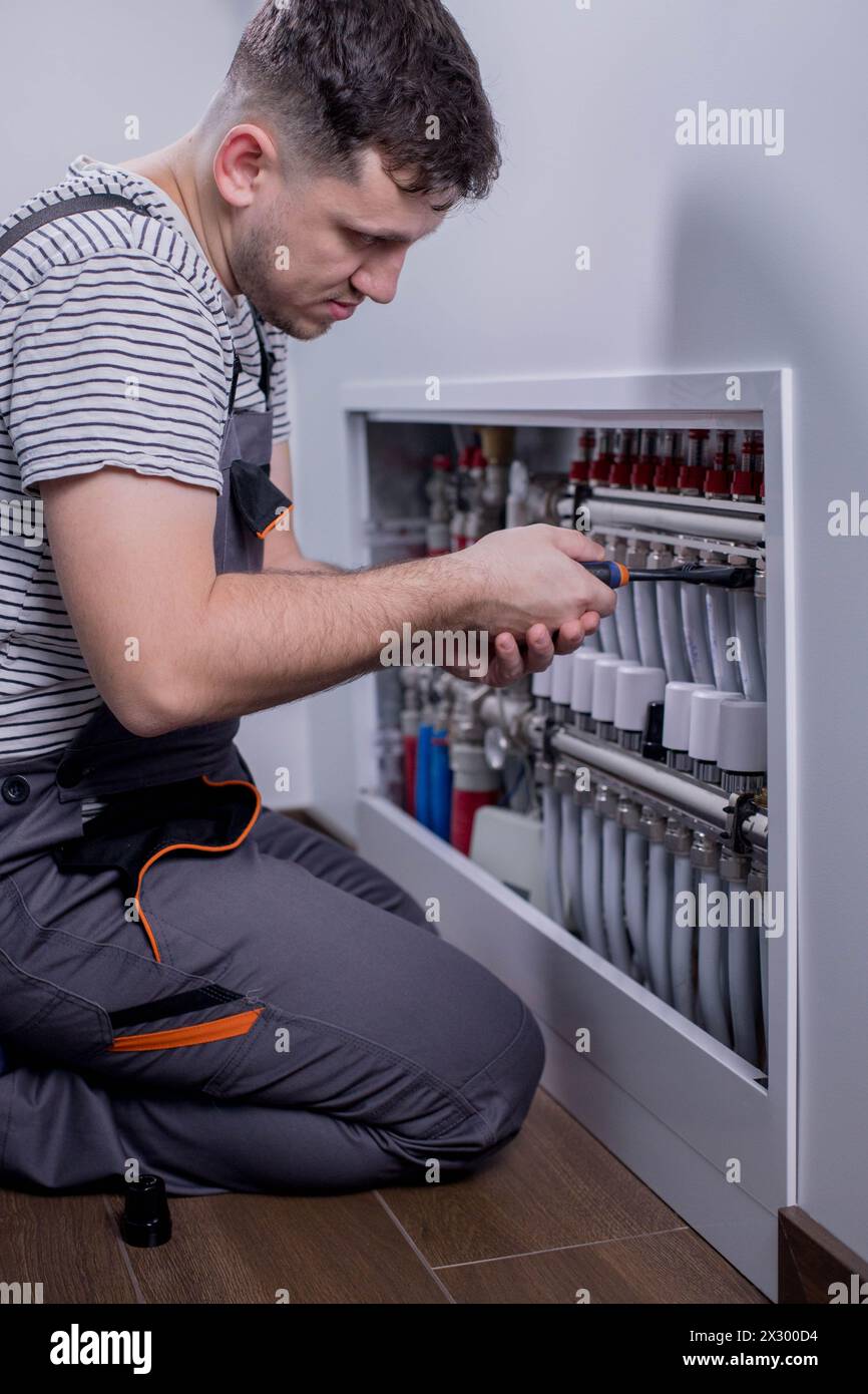Plumber work. Installing collector for warm water underfloor heating system. Stock Photo