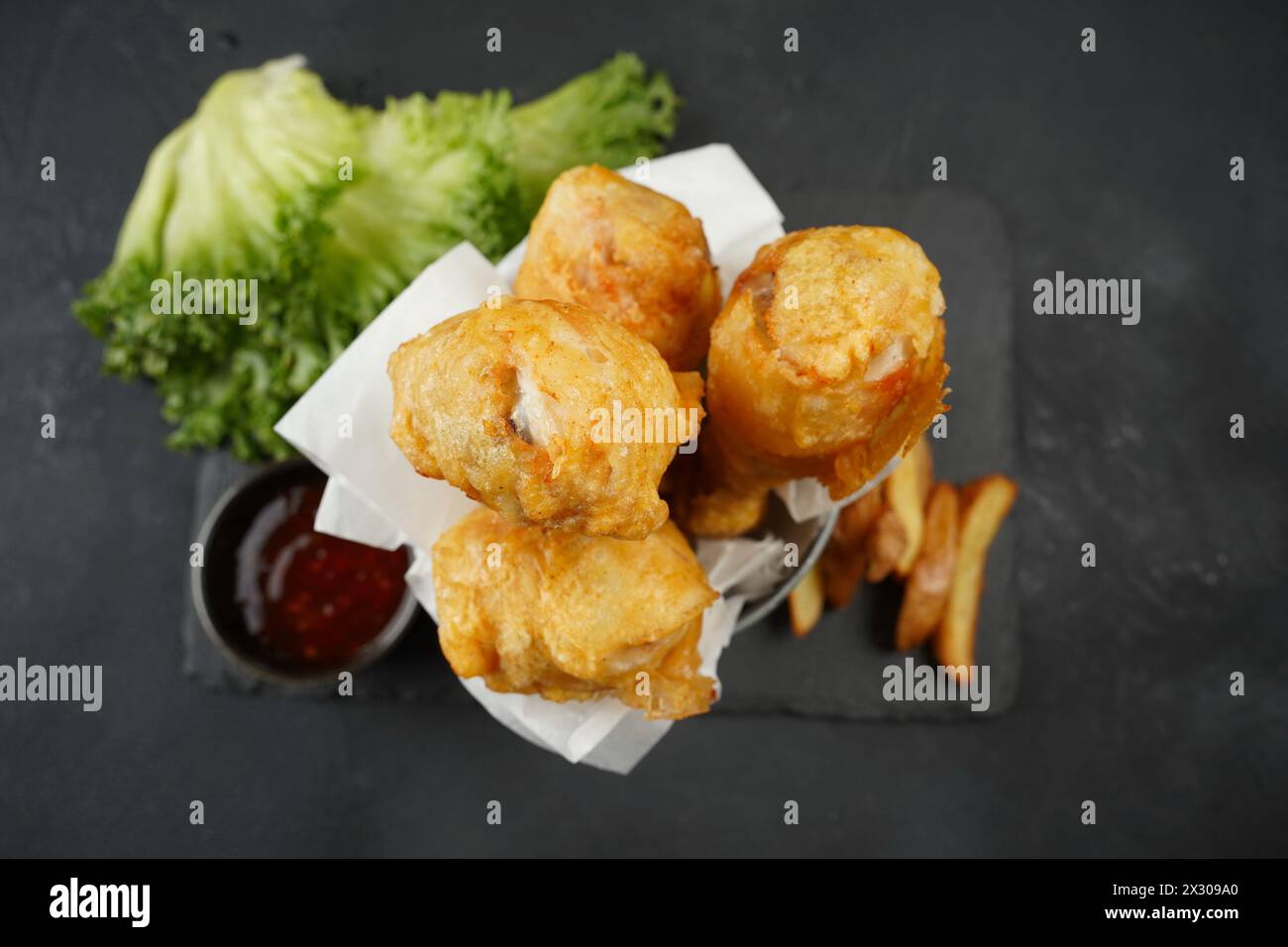 Fried chicken drumsticks in batter with hot sauce and lettuce Stock Photo