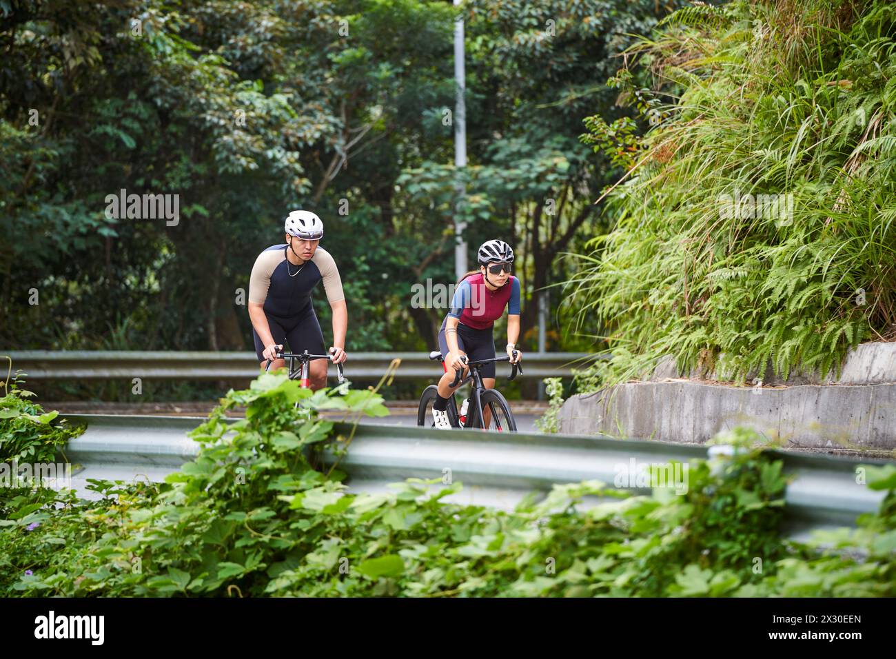 young asian couple cyclists riding bike on rural road Stock Photo