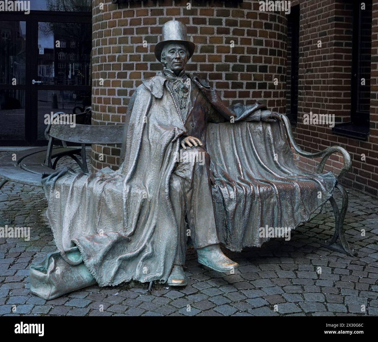 shimmering bronze statue of H C Andersen in top hat sitting on a bench, Odense, Denmark, April 19, 2024 Stock Photo