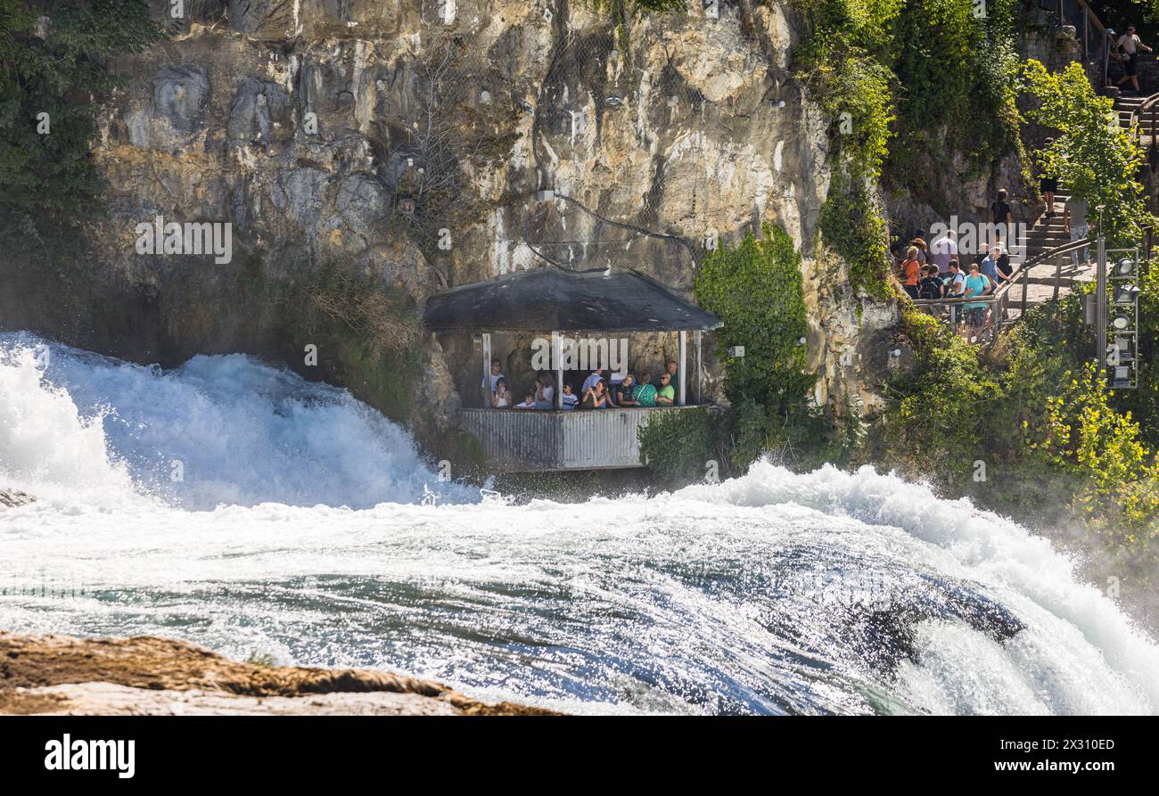 In einer Kanzel, welche auf dem Gebiet des Kanton Zürich liegt, beobachten Touristen den Rheinfall aus unmittelbarer Nähe. (Neuhausen am Rheinfall, Sc Stock Photo