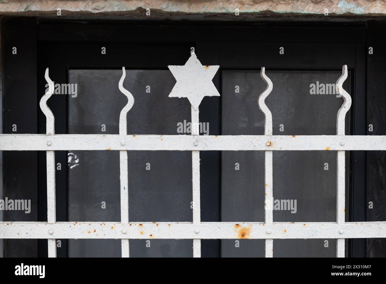 A metal grate with sharp, pointed rods and a small Jewish star of David ...