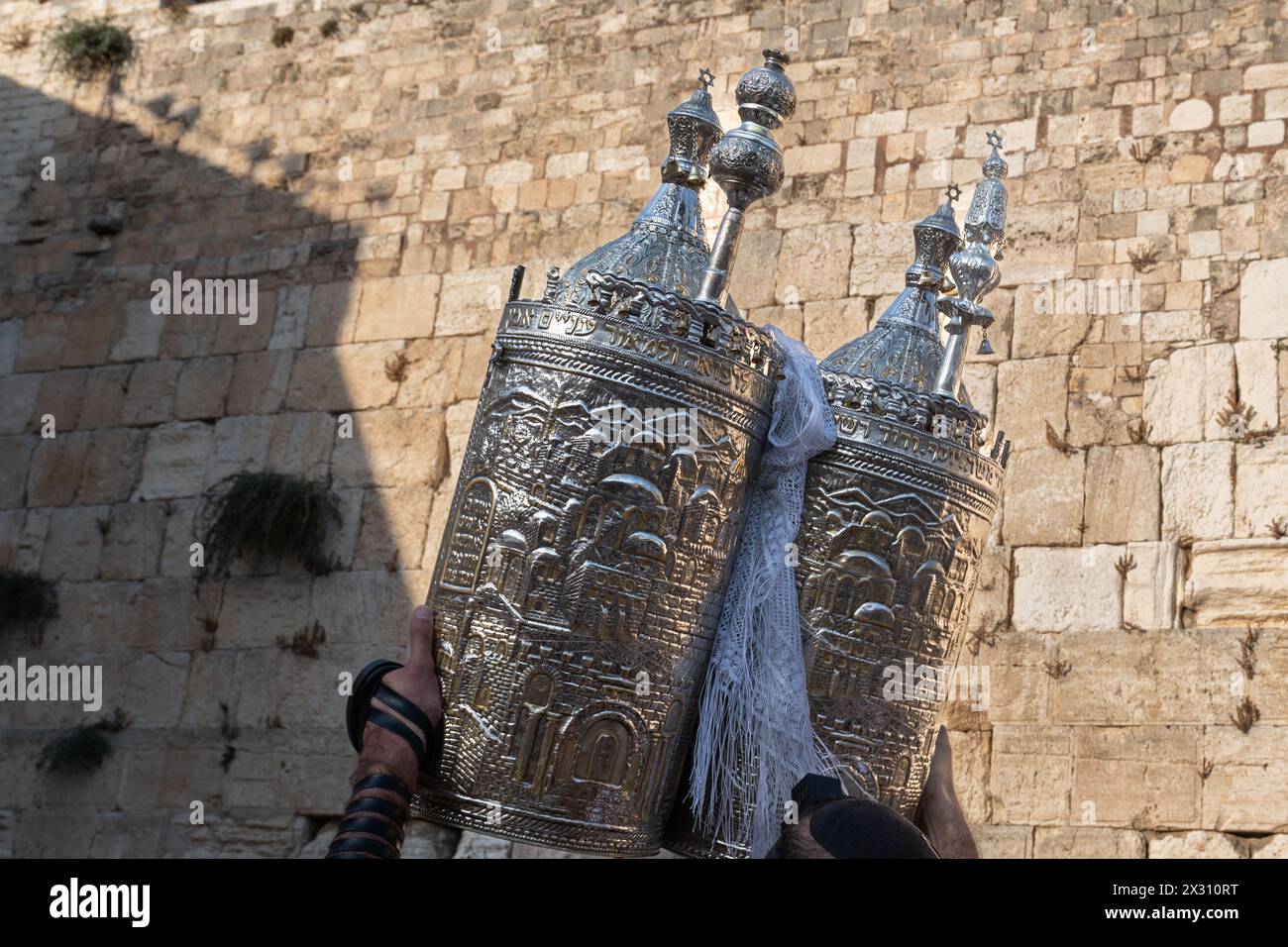 A sefardi Torah scroll is lifted toward the sky during afternoon Jewish prayers on the holiday of Tisha B'Av at the Western Wall in Jerusalem, Israel. Stock Photo