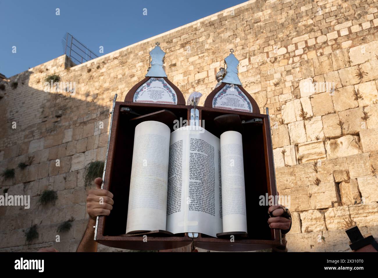 A sefardi Torah scroll is lifted toward the sky during afternoon Jewish prayers on the holiday of Tisha B'Av at the Western Wall in Jerusalem, Israel. Stock Photo