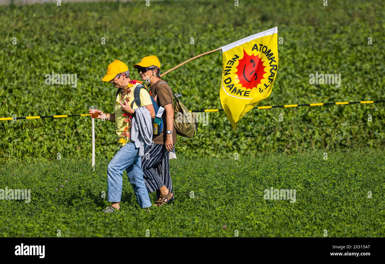 Zwei Anti-Atomdemonstrantinnen mit der bekannten Flagge der Atomkraftgegner laufen über eine saftig, grüne Wiese. (Marthalen, Schweiz, 30.08.2022) Stock Photo