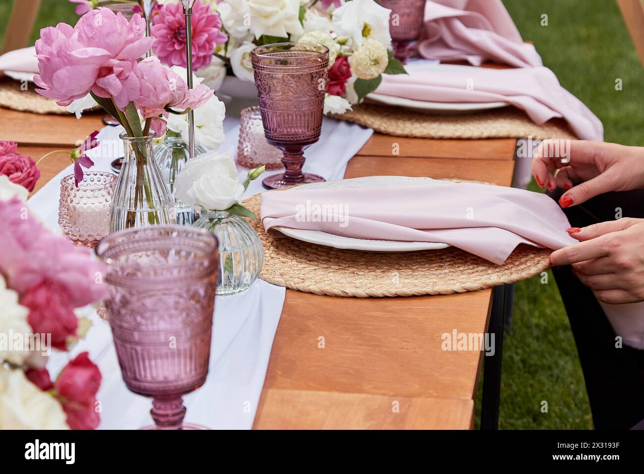 Picnic aesthetics table setting, flowers arrangement. Tabletop with floral decoration and place settings. Dining etiquette and table decor concept. Stock Photo