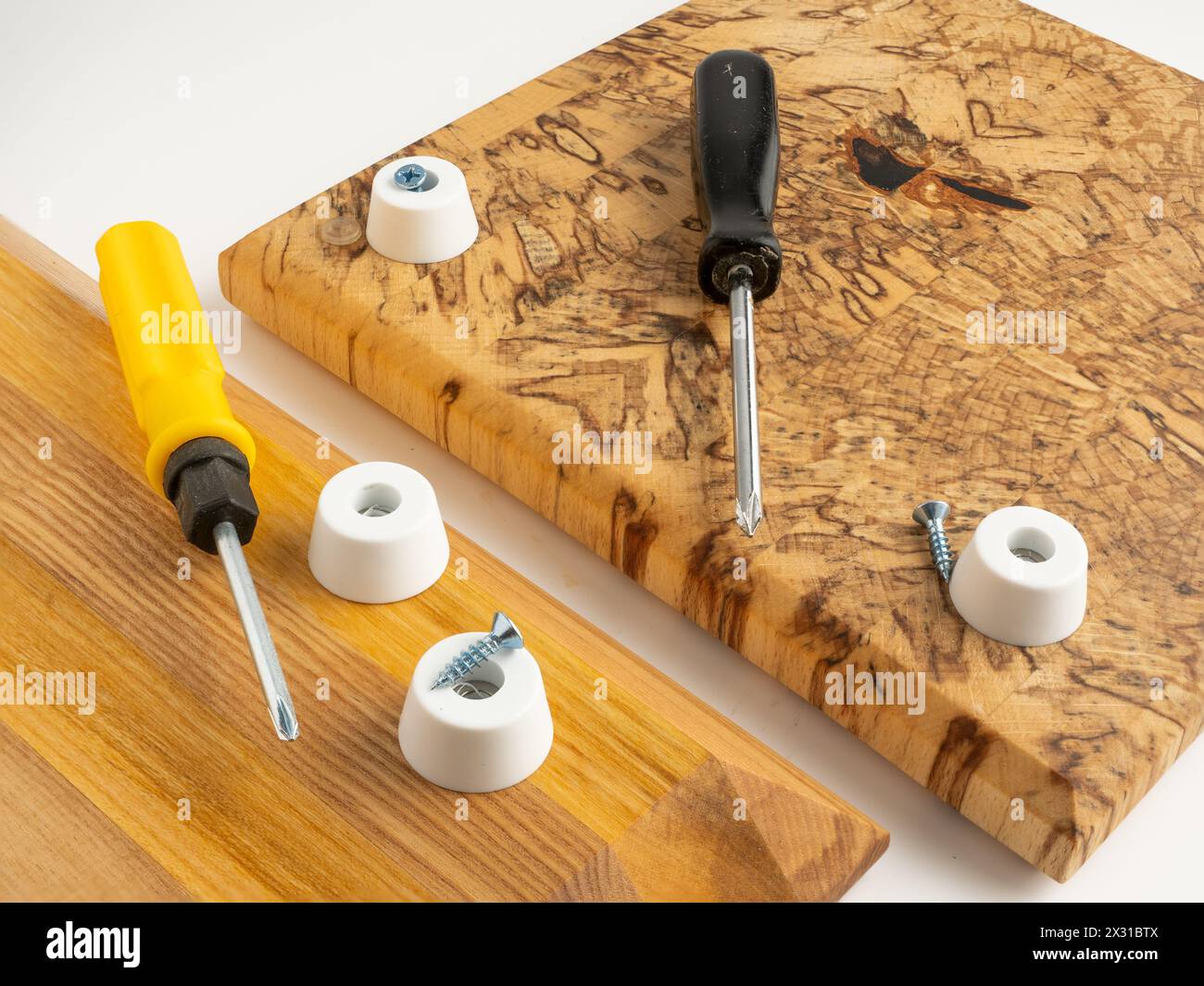 White plastic rubber bumper ffeet ,pads being fitted to wooden cutting boards with stainless