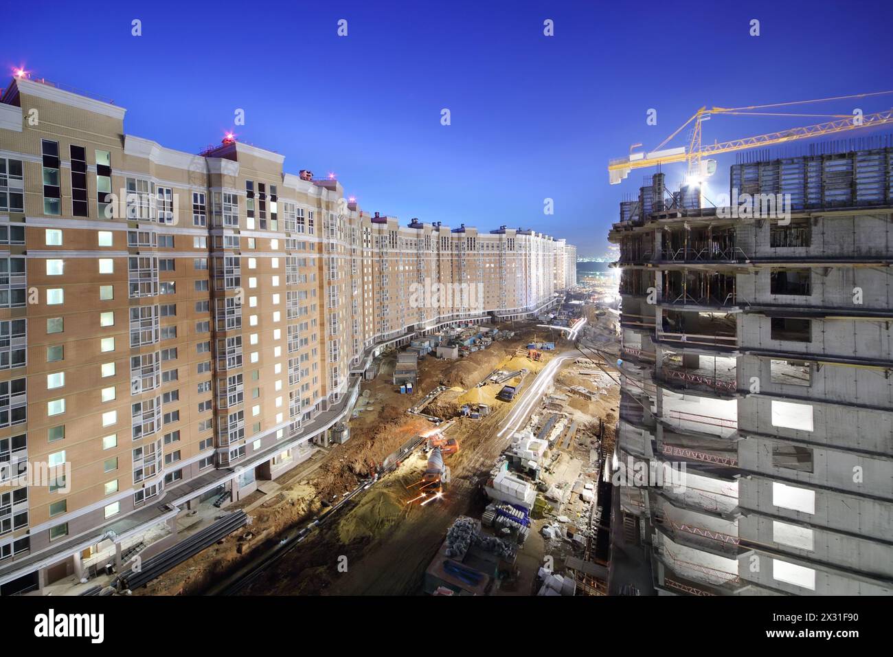 Long high multi-storey buildings under construction and construction site at night. Stock Photo