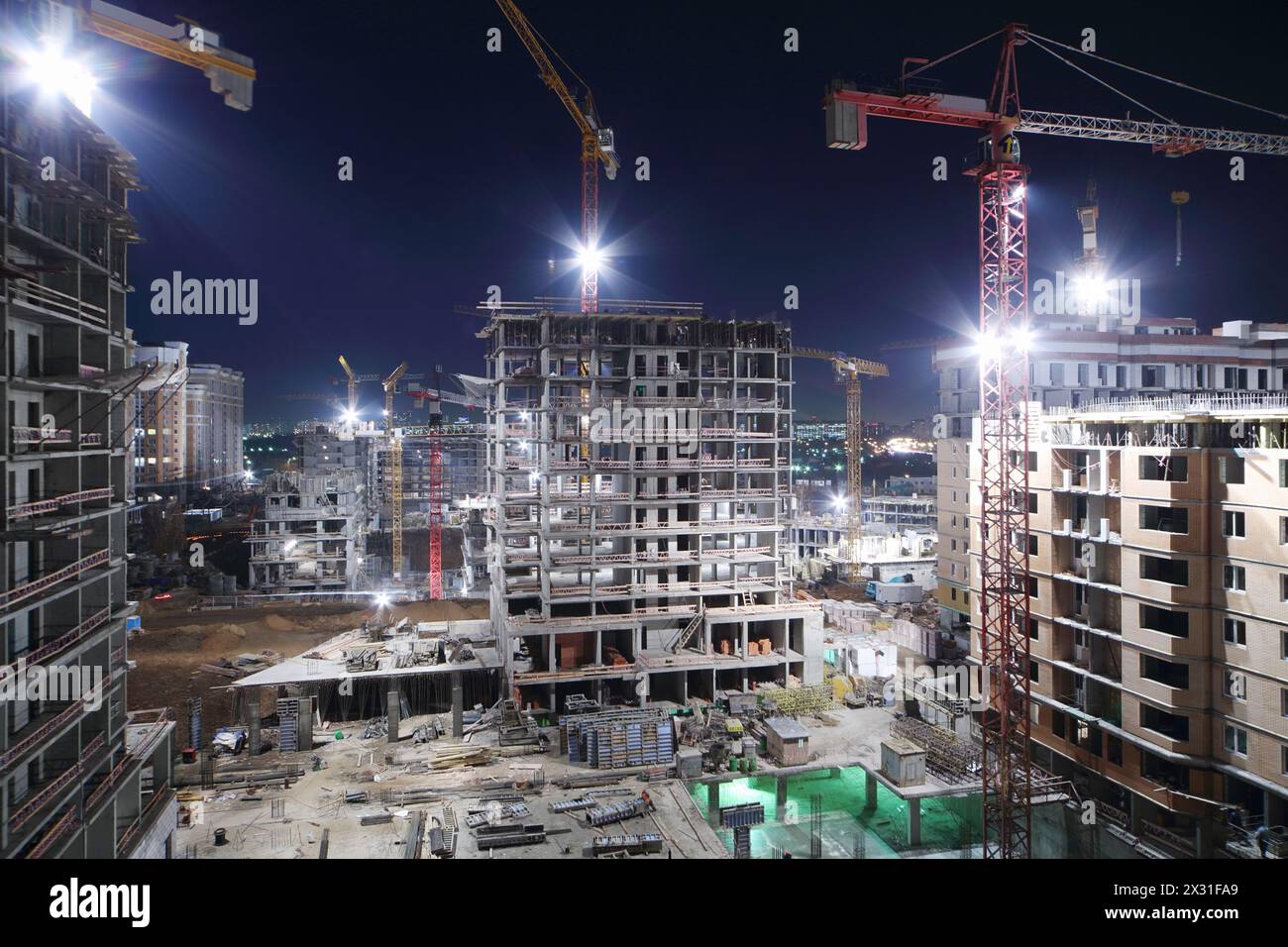Lightening multi-storey buildings under construction and cranes at night. Stock Photo