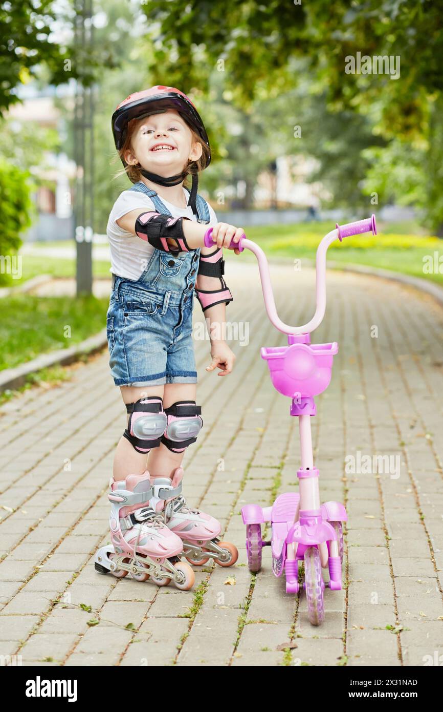Smiling little girl in roller and protective equipment stands on