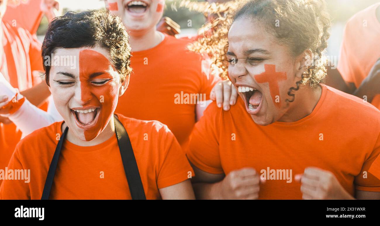 Orange sport fans having fun supporting their team - Football supporters having fun at competition event - Focus on african girl face Stock Photo