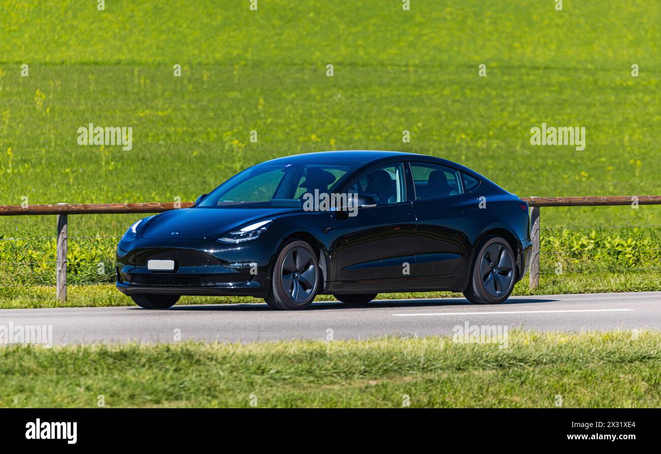 Ein Tesla Model 3 fährt auf einer Strasse ausserorts im