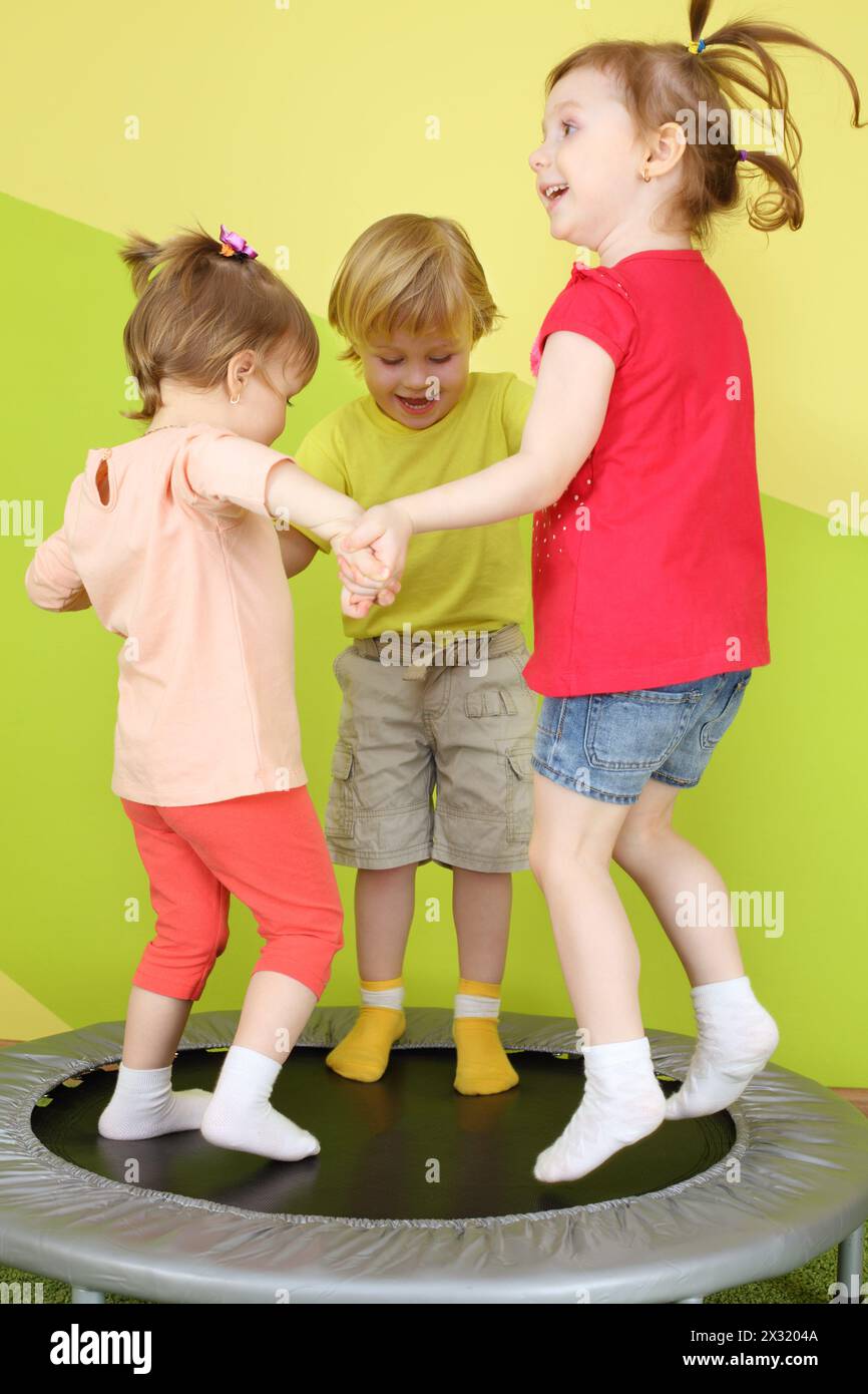 Two girls and a boy jumping on a small trampoline joining hands Stock ...