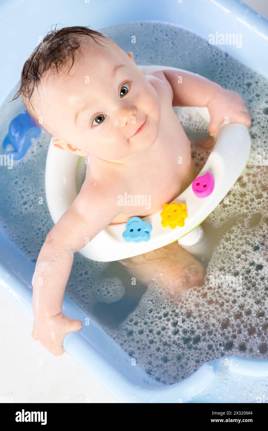 Cute baby girl bathes in a bathtube with toys Stock Photo