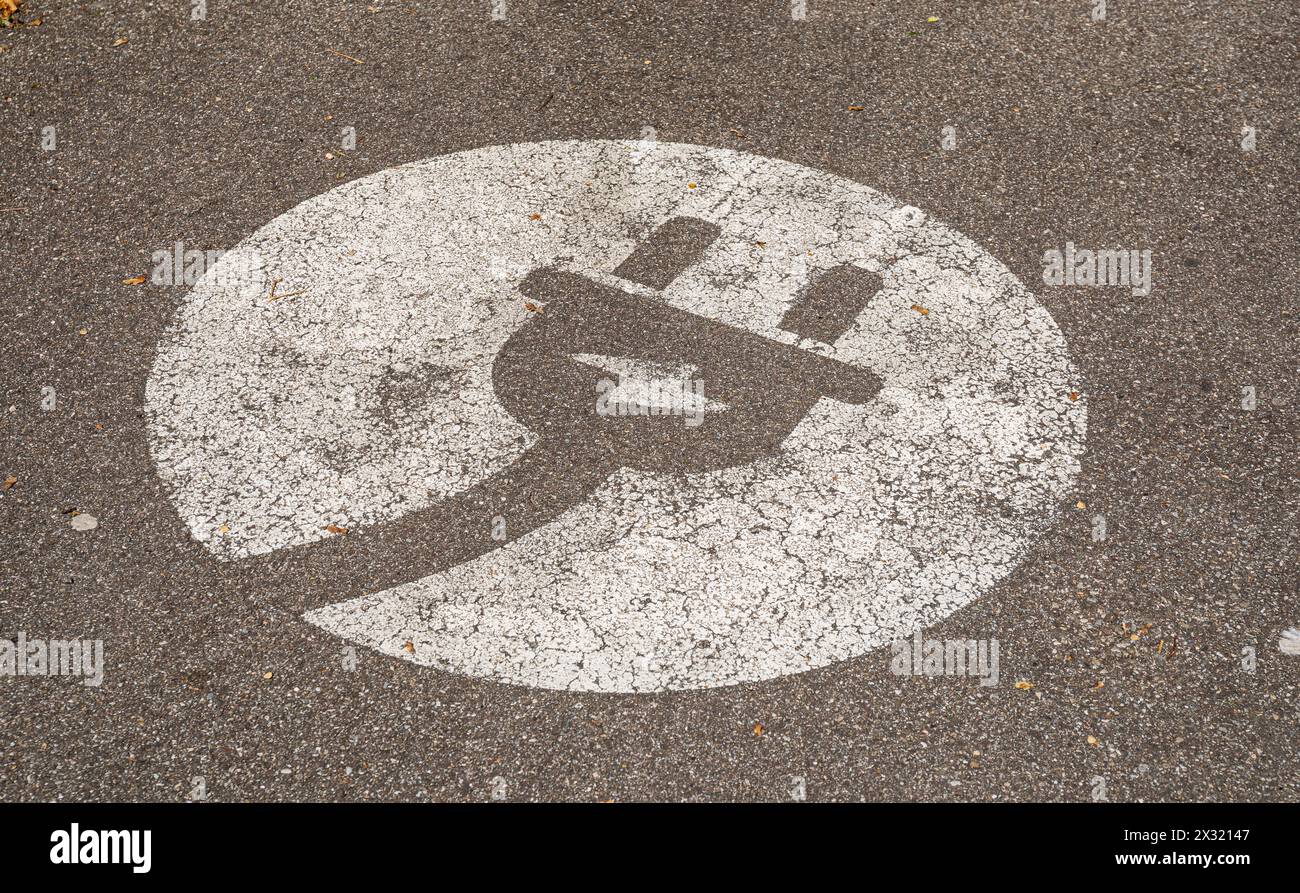 Ein Steckersymbol auf einem Parkplatz symobilisiert, das hier Elektroautos geladen werden können. (Rheinfelden, Schweiz, 13.04.2022) Stock Photo